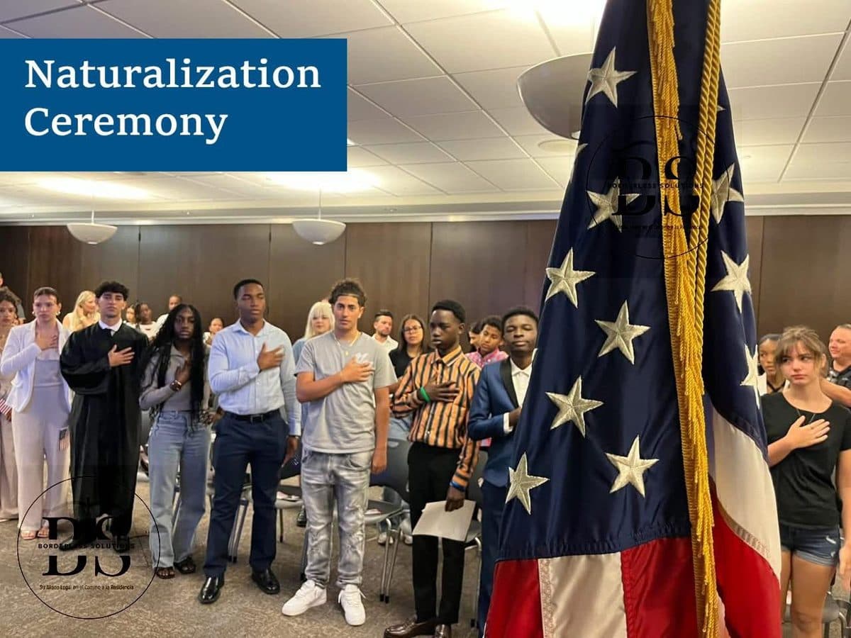 New citizens taking the oath at a naturalization ceremony with a U.S. flag